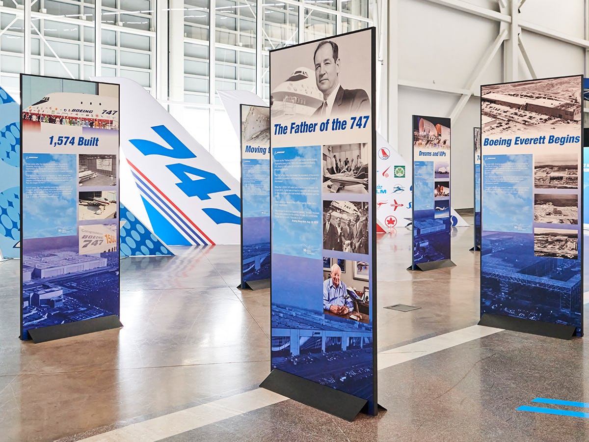 Tall, vertical signs on the Gallery floor display information about the iconic Boeing 747 history and legacy, as well as various visuals such as graphics and photography of the plane making its way from the Boeing Everett factory floor to the skies.