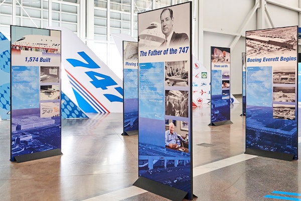 Tall, vertical signs on the Gallery floor display information about the iconic Boeing 747 history and legacy, as well as various visuals such as graphics and photography of the plane making its way from the Boeing Everett factory floor to the skies.