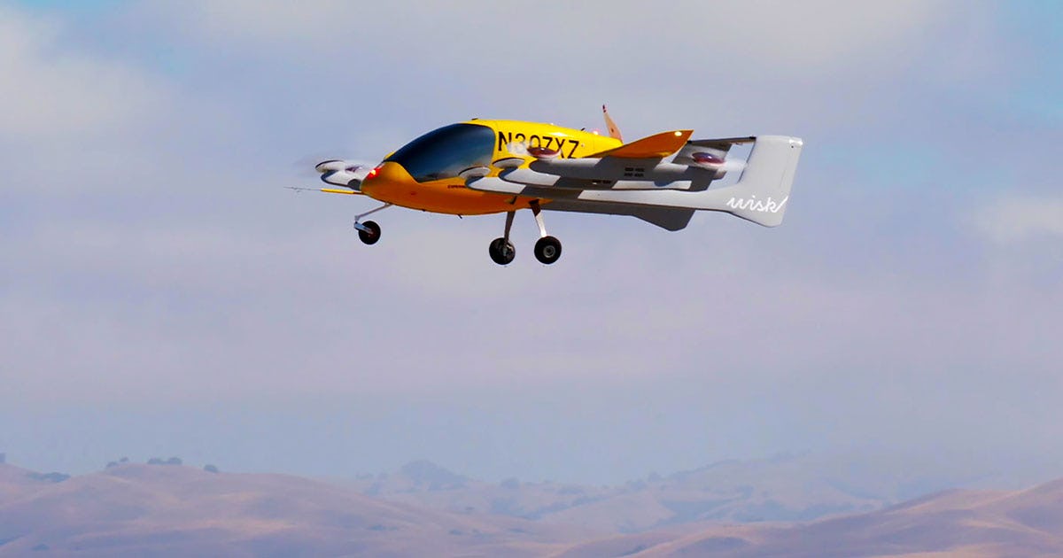 Wisk Aero Gen 5 hovering in the air, with a light haze and the silhouette of mountains in the distance.