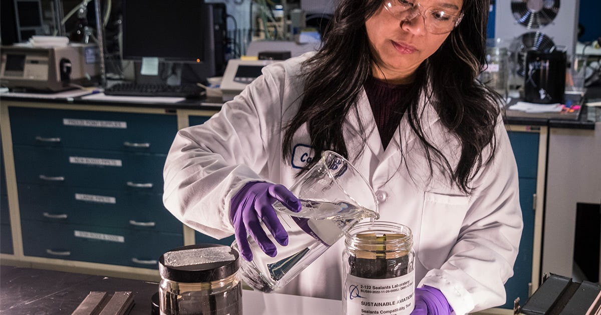 A Boeing materials, process and physics engineer pours the jet reference fluid into a jar for sealants immersion testing.