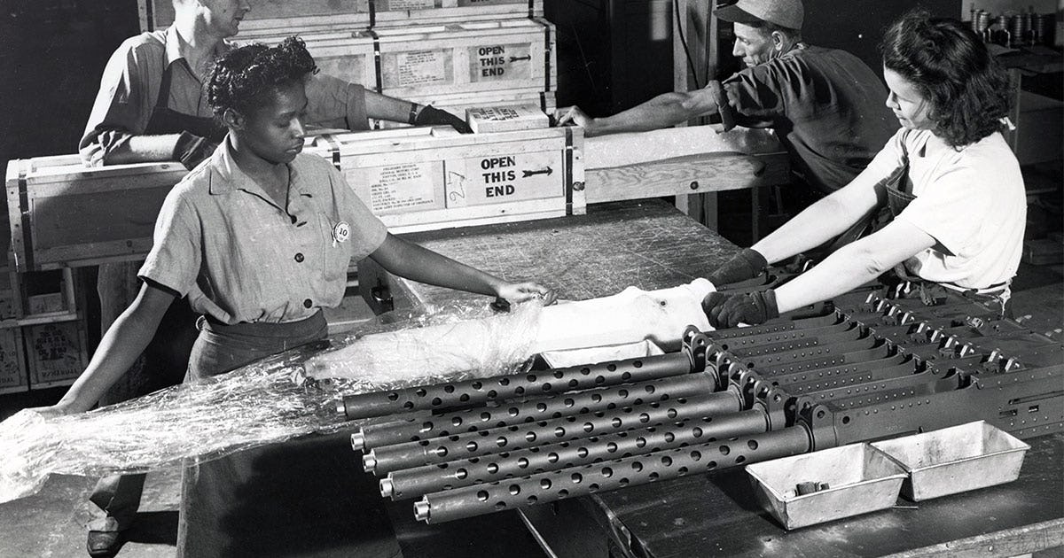 A black and white image of our "Rosies" packing up airplane gunning equipment together.
