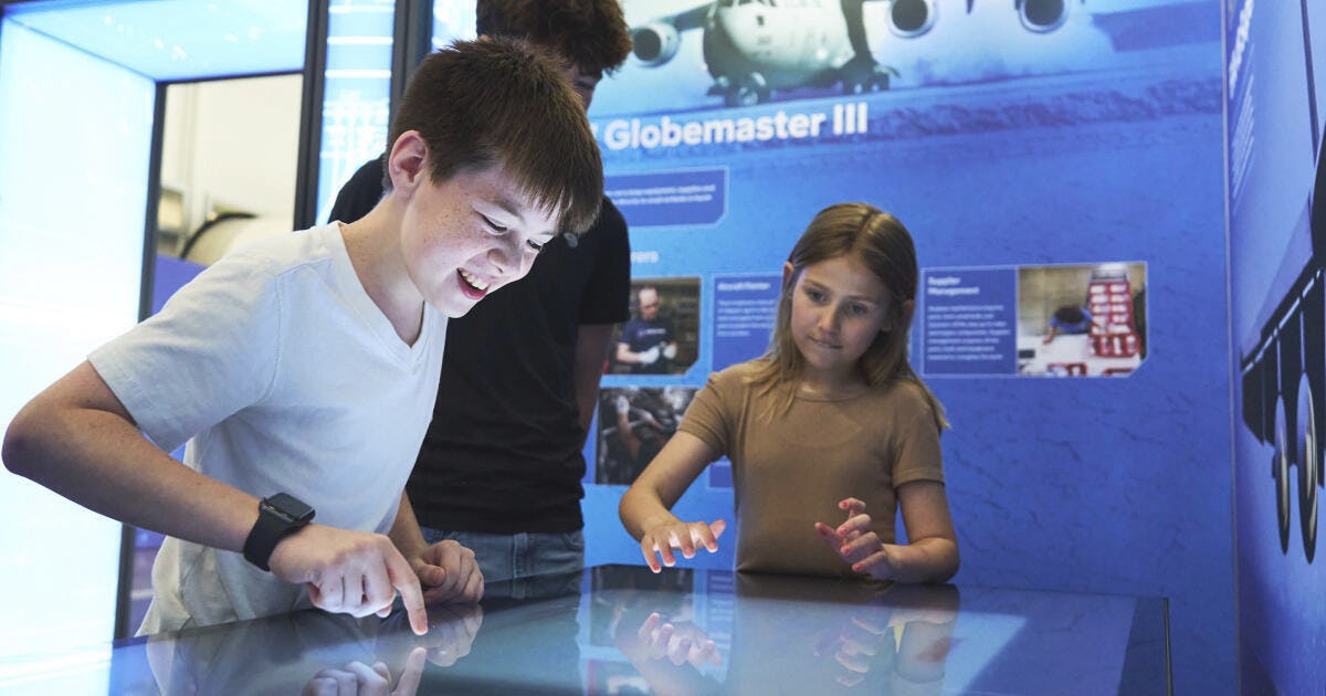 Kids learning gathered around a backlit table, learning about Boeing aerospace.