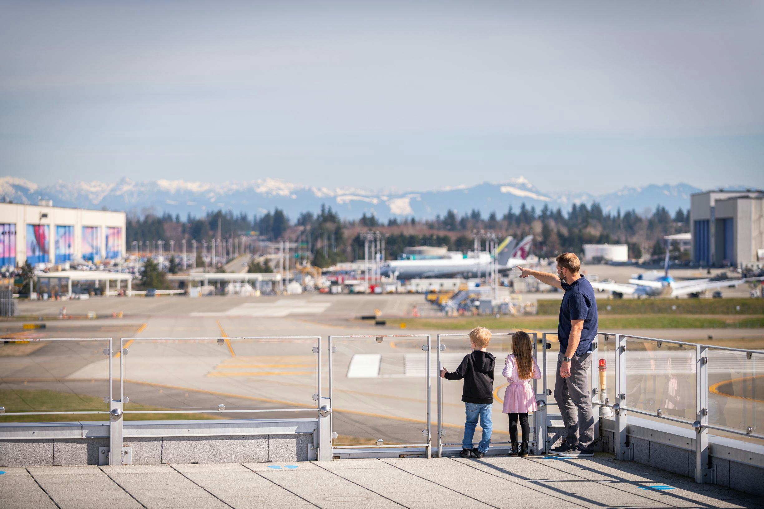 a dad with young kids stand on the sky deck and look at Paine Field